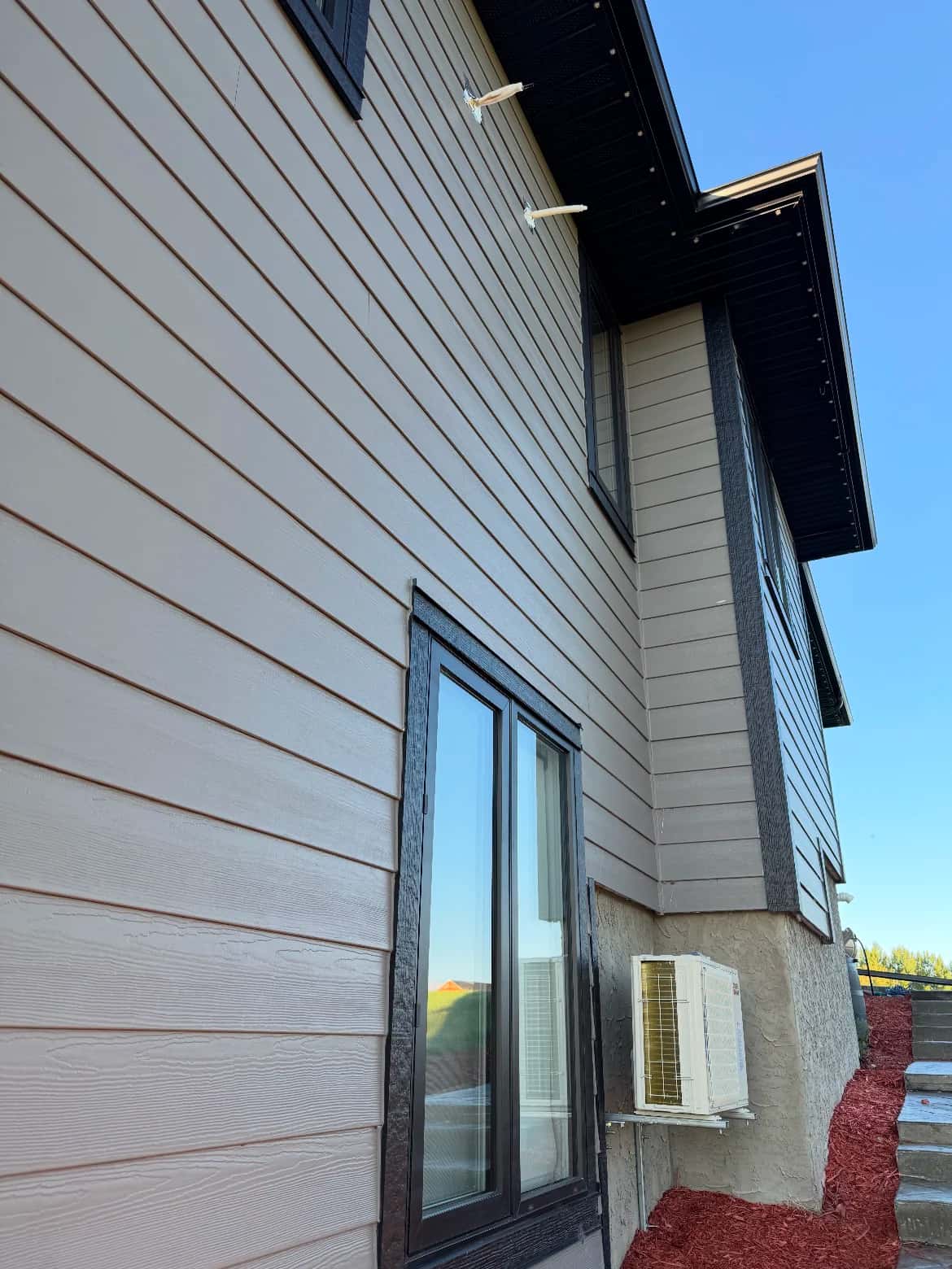 New lap siding with dark trim and a wall-mounted mini-split heat pump on a residential exterior