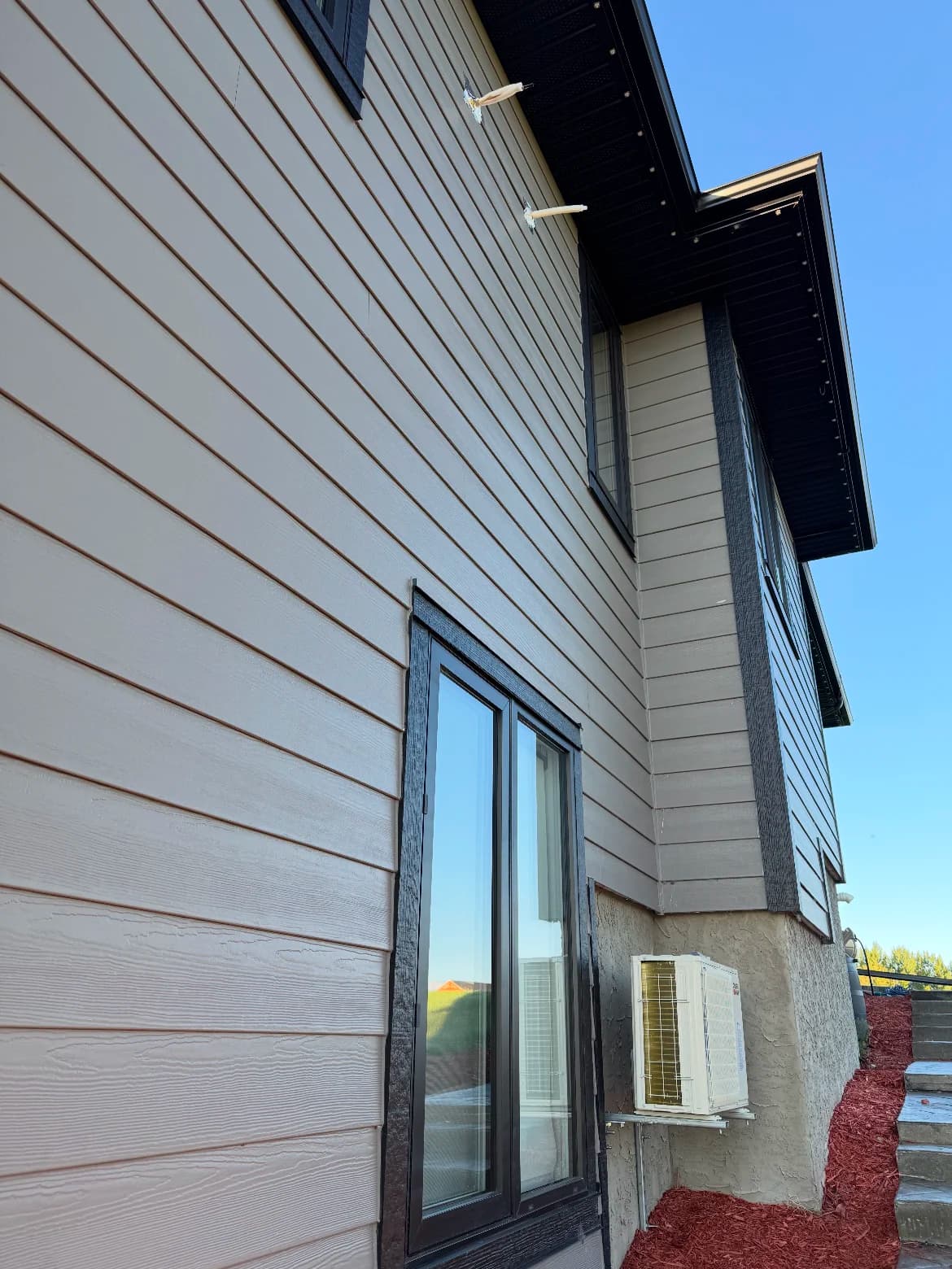 New lap siding with dark trim and a wall-mounted mini-split heat pump on a residential exterior