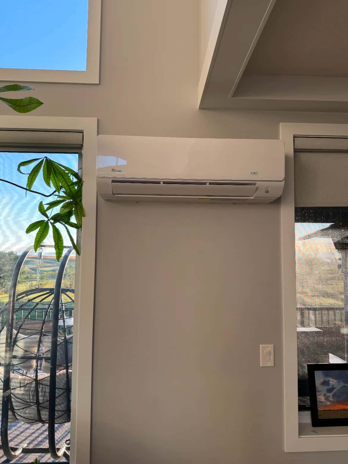 Ductless mini-split head mounted high on a bright living room wall