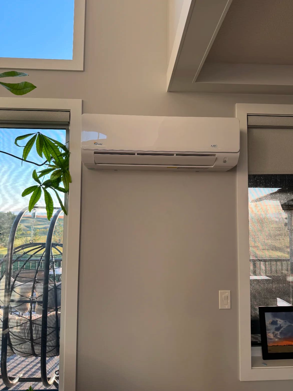 Ductless mini-split head mounted high on a bright living room wall