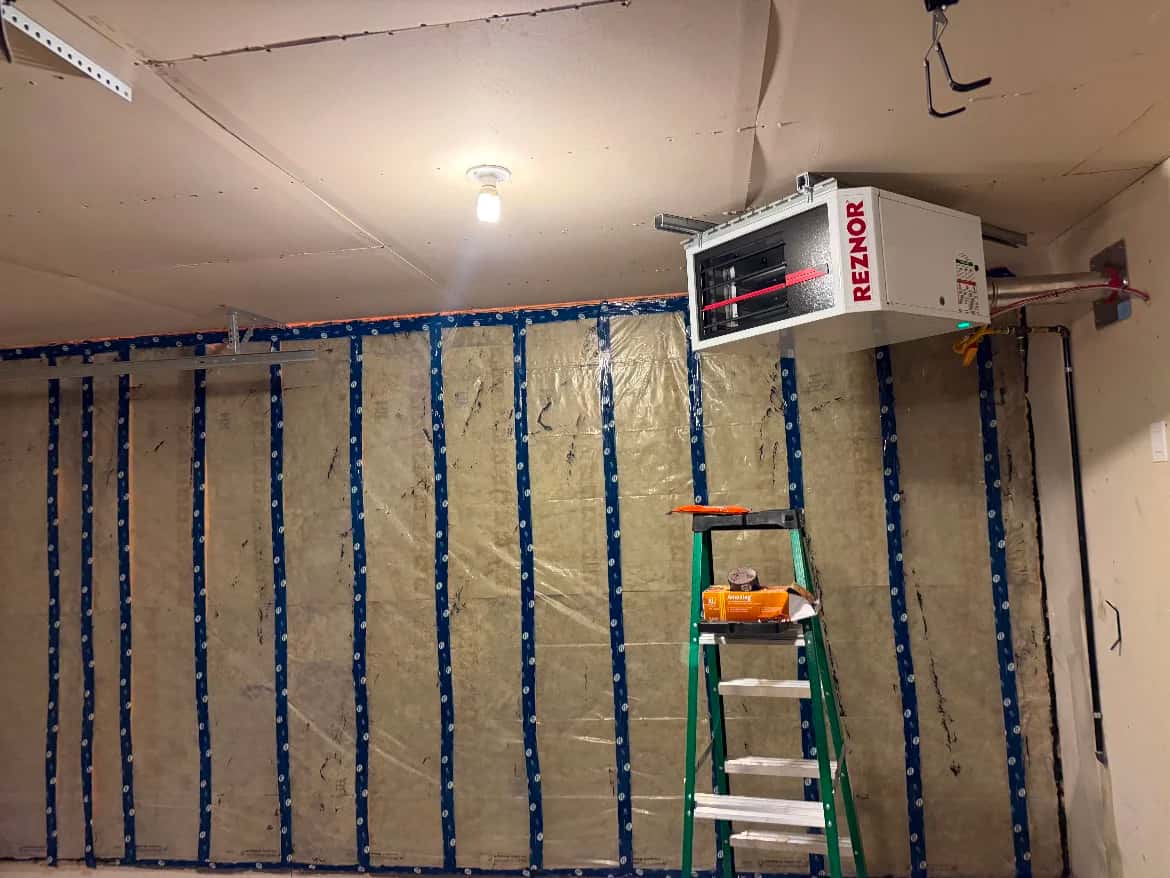 Gas unit heater hung at the ceiling of a garage with insulated walls in progress