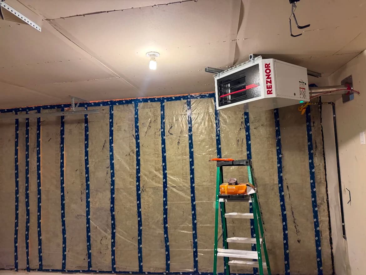 Gas unit heater hung at the ceiling of a garage with insulated walls in progress