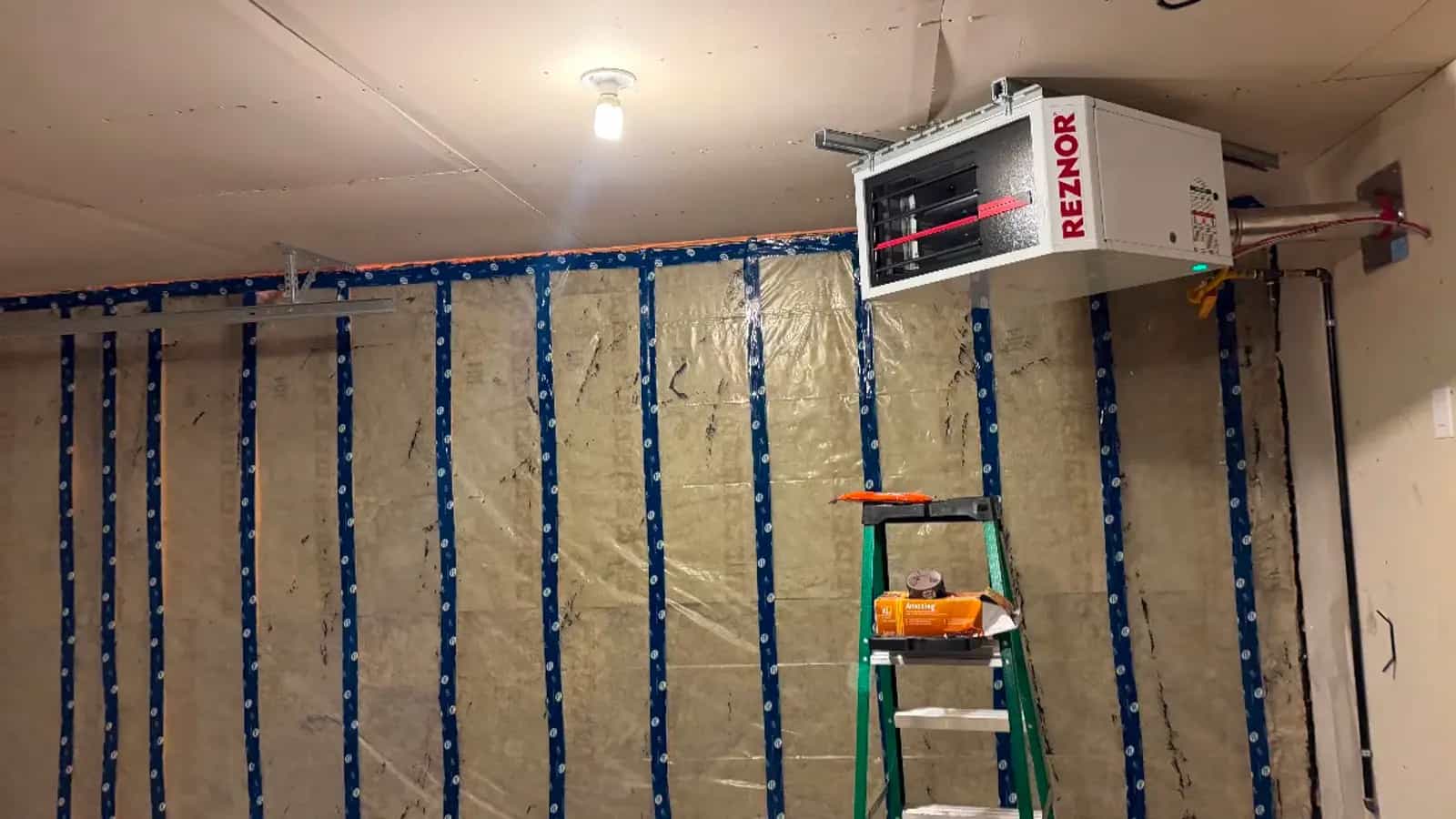 Gas unit heater hung at the ceiling of a garage with insulated walls in progress