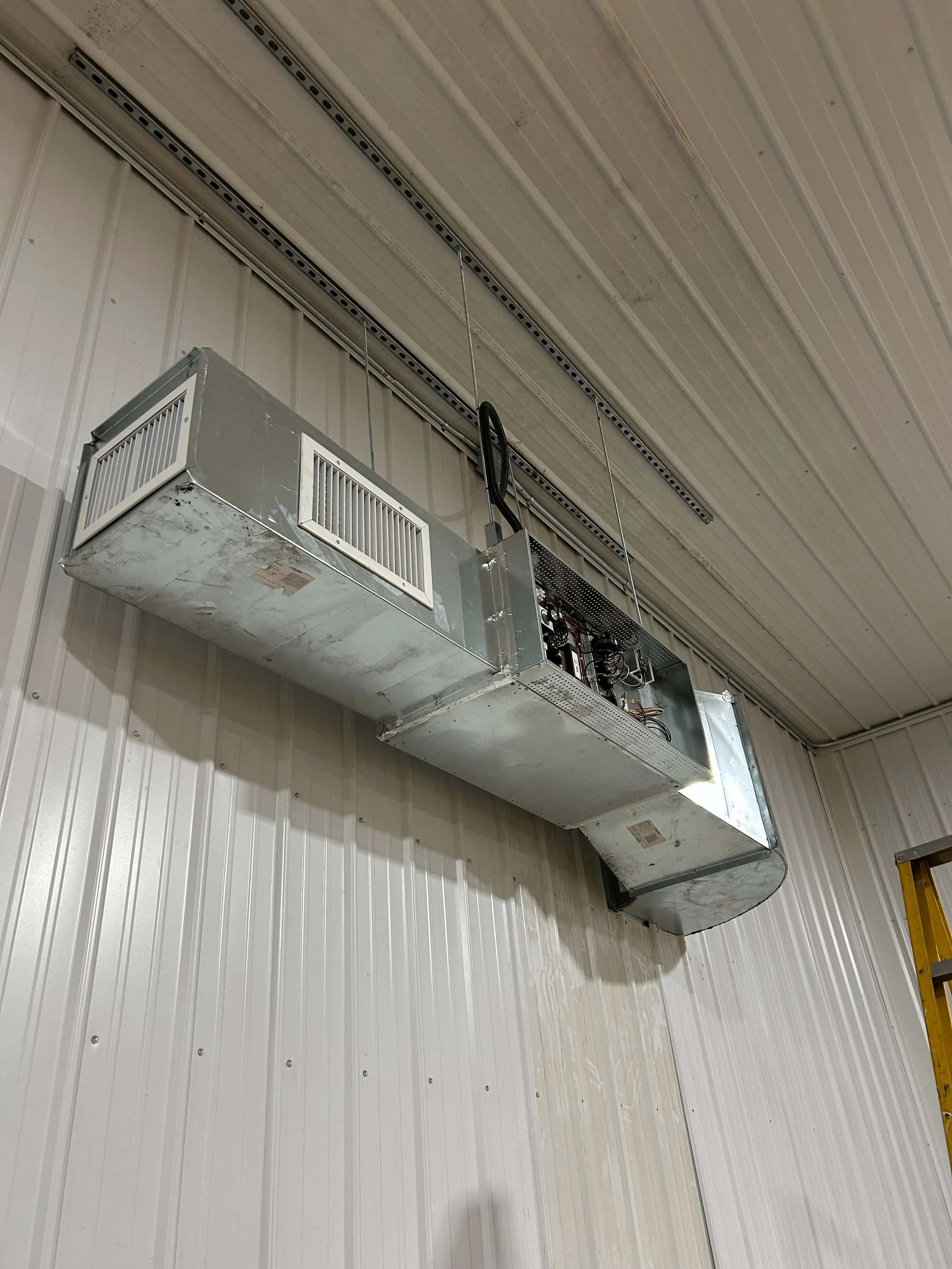 Custom sheet-metal ventilation unit hung high on an arena wall