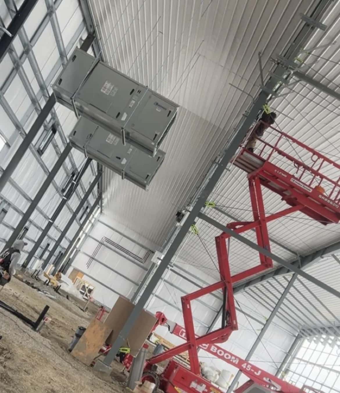 Air-handling units rigged high against the structure of a steel building during installation