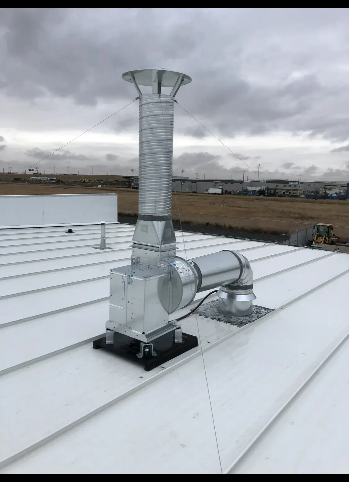 Guyed exhaust stack and inline fan on a standing-seam metal roof