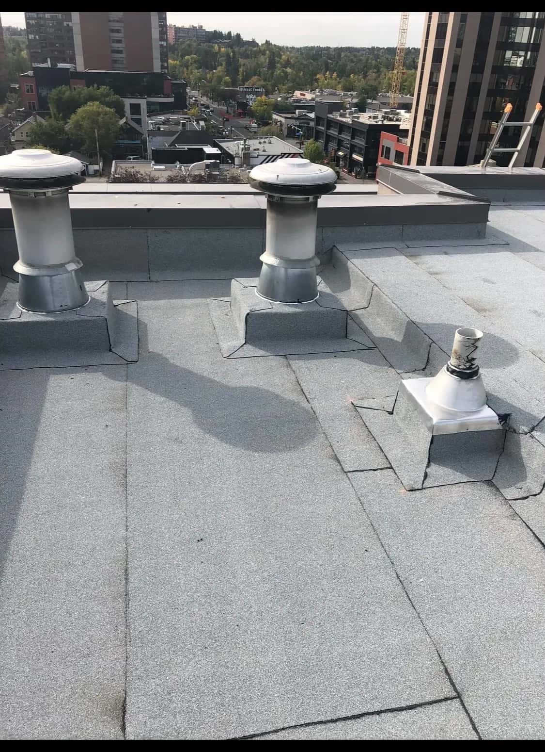 Granulated torch-on membrane roof with vents overlooking city rooftops
