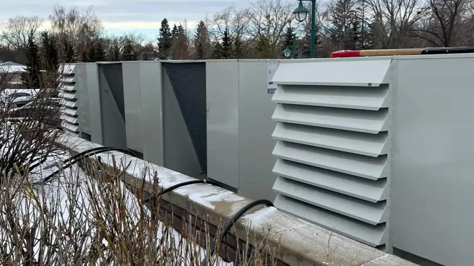 Bank of condensing units lined up behind a masonry screen wall in winter