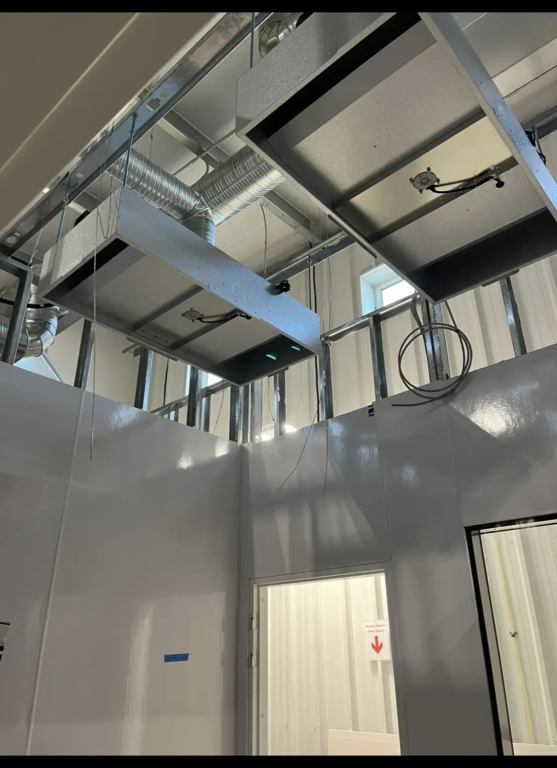 HEPA fan housings and ducting above a cleanroom ceiling grid