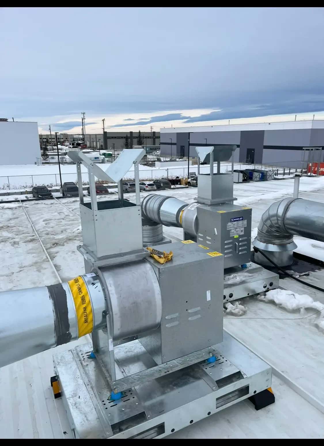 Rooftop exhaust fans mounted on vibration-isolated bases with wind guards