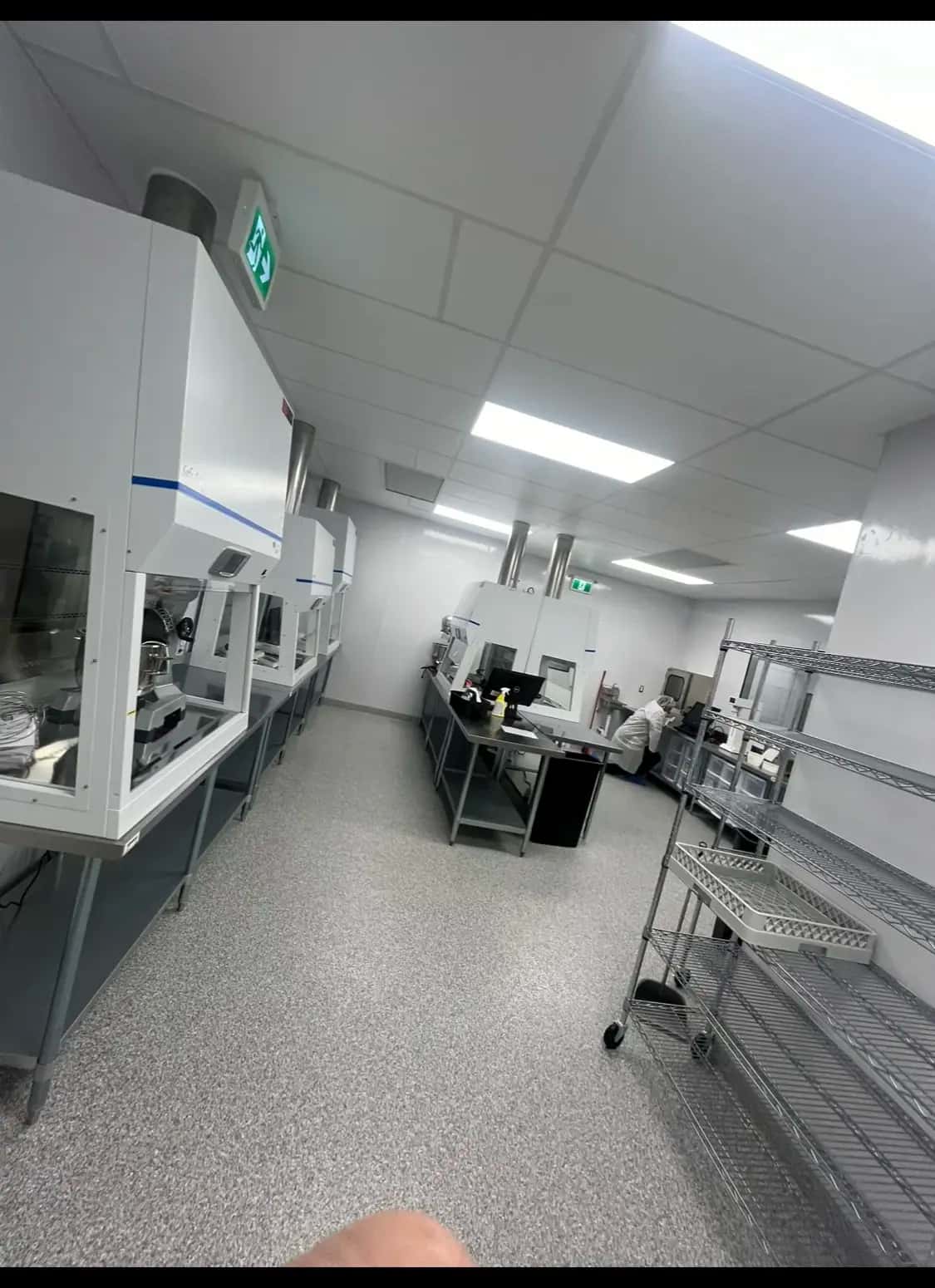 Gowned technician working among biosafety cabinets in a finished compounding lab