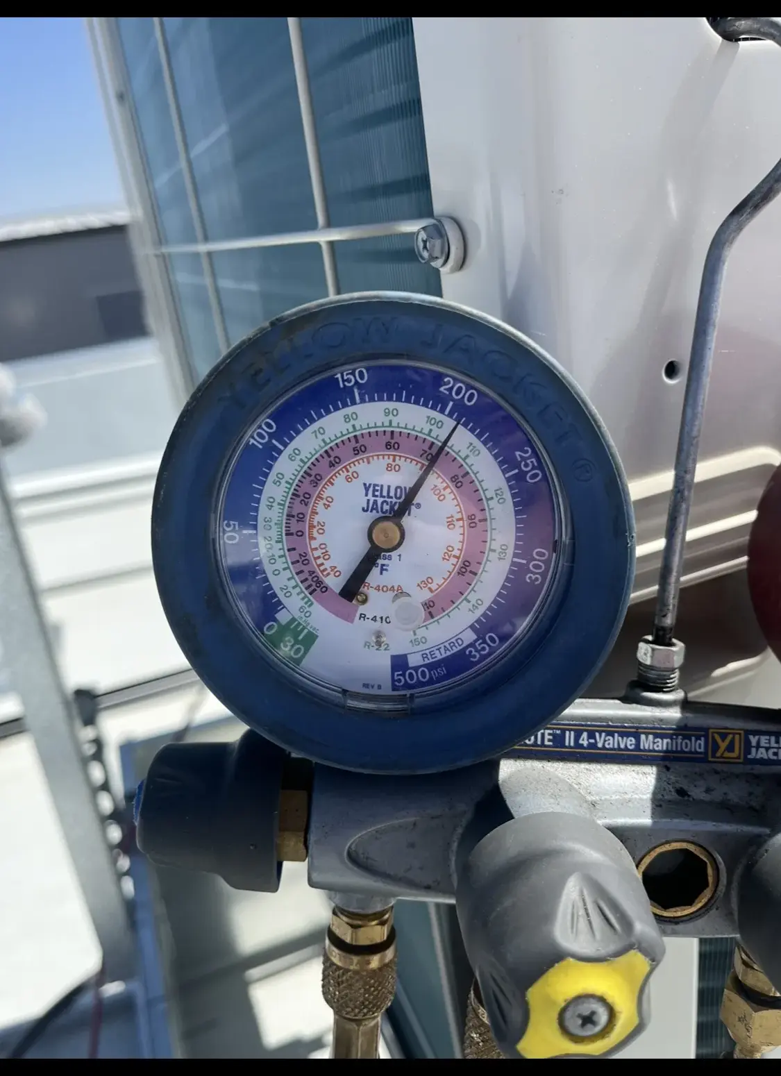 Refrigerant manifold gauges connected during rooftop unit service