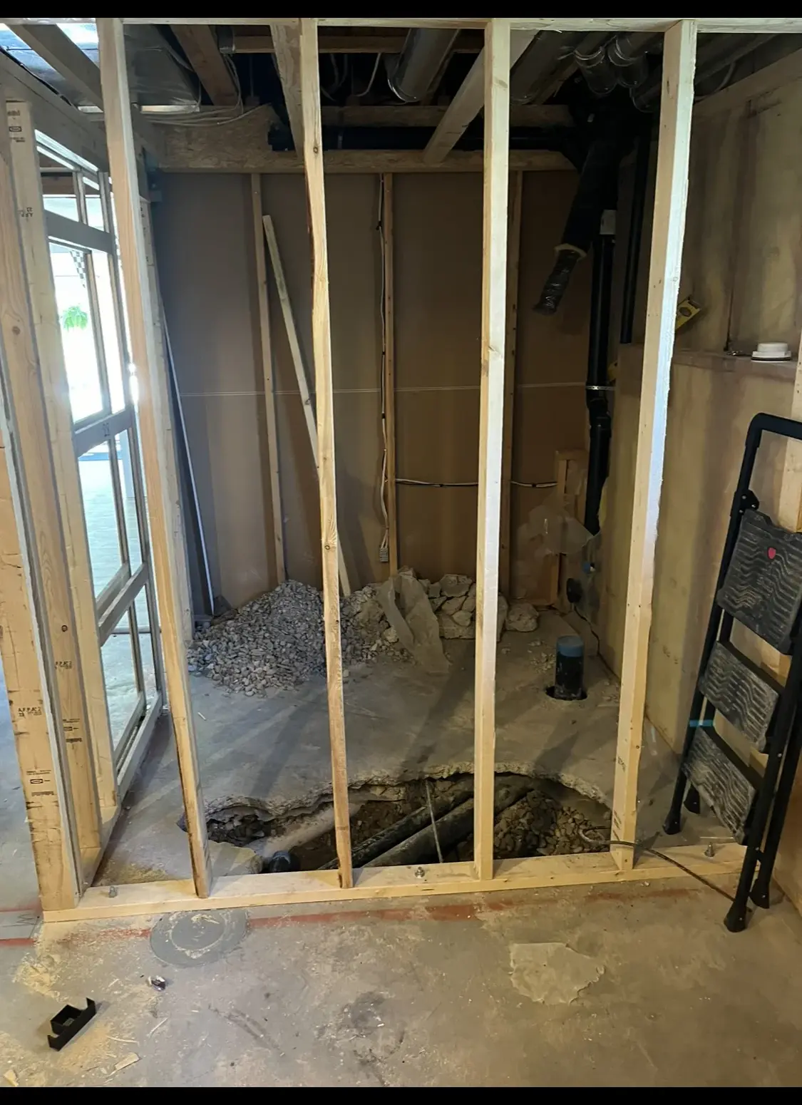 Basement bathroom framing with an excavated trench for new under-slab drains