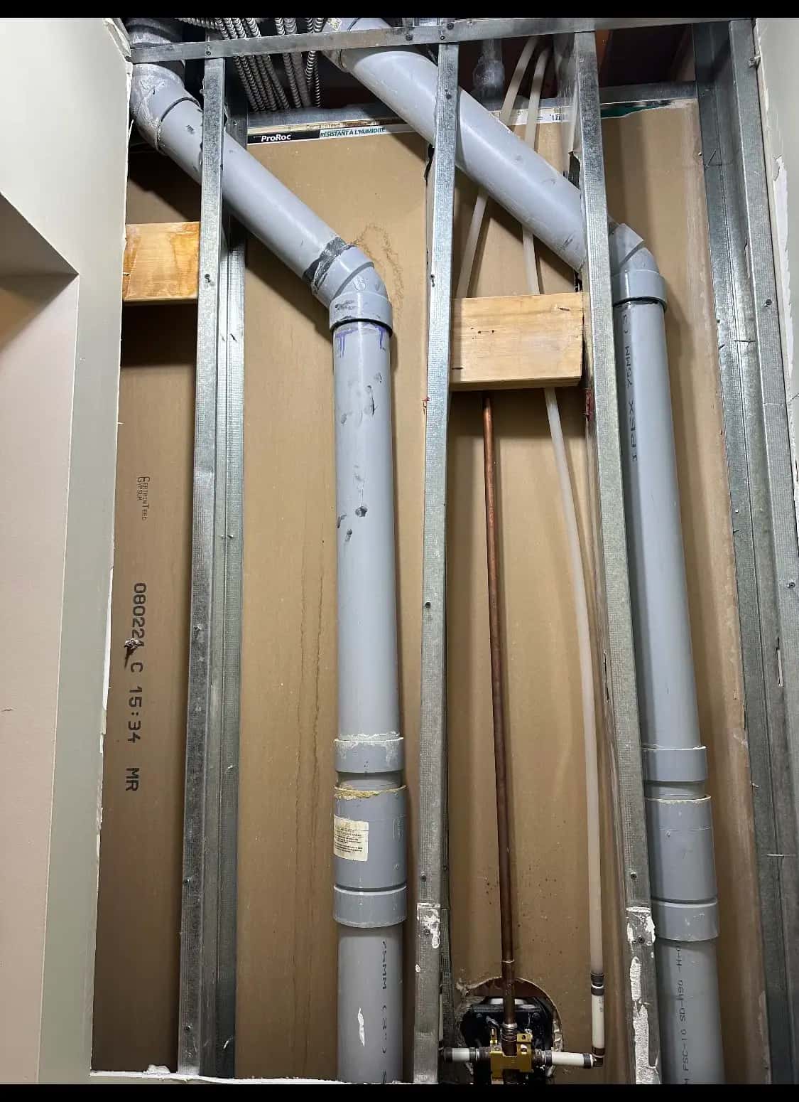 New PVC drain, copper and PEX risers run behind steel studs during a renovation