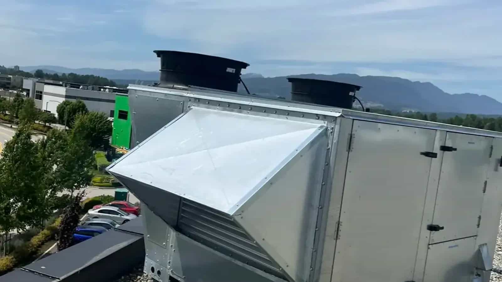 Rooftop air unit with weather hood and exhaust fans on a gravel ballast roof