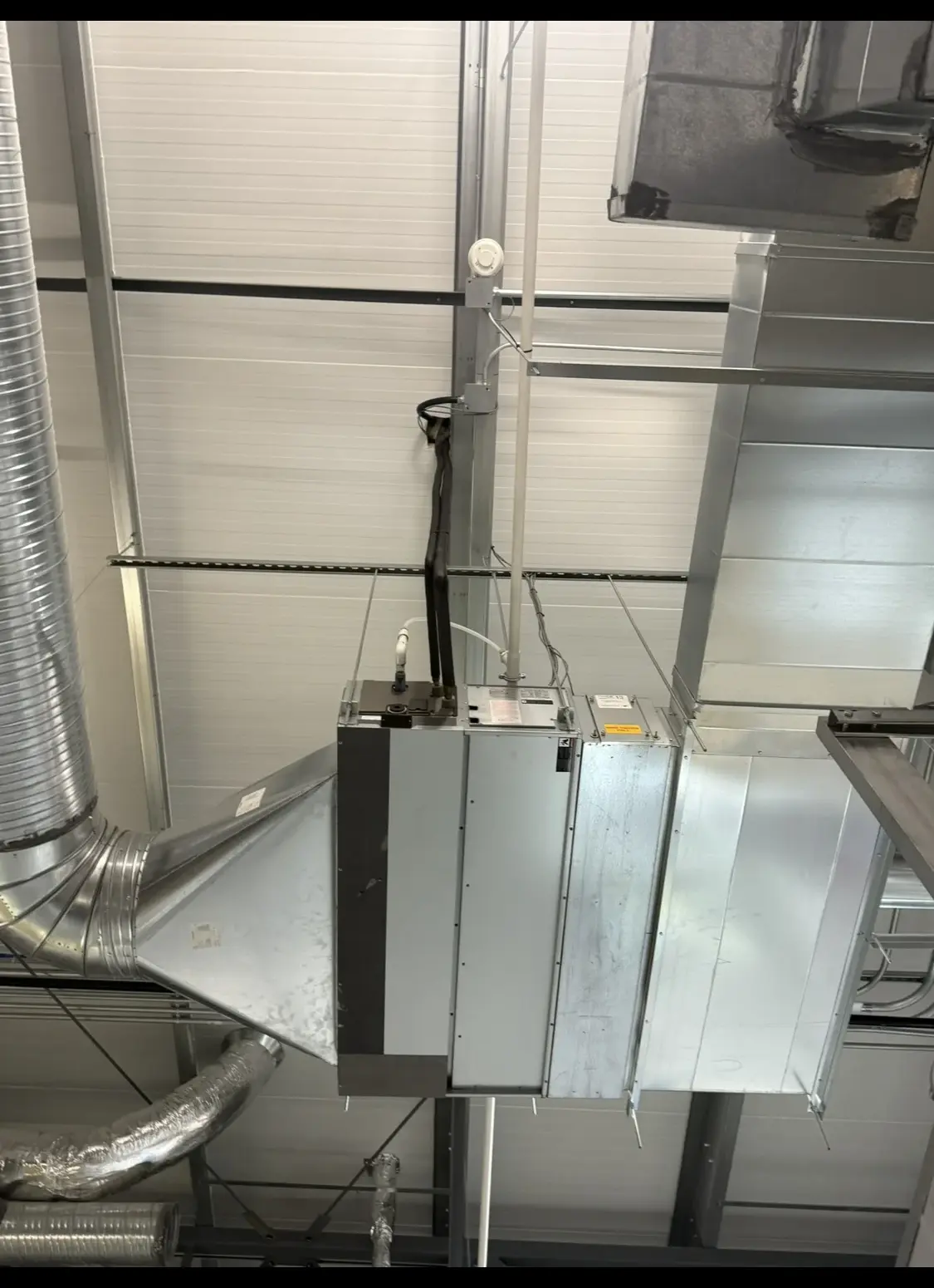 Suspended air-handling unit with a tapered transition duct at a commercial ceiling